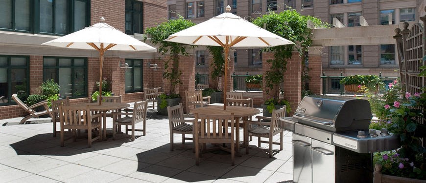 an outdoor patio with tables and umbrellas and a barbecue grill