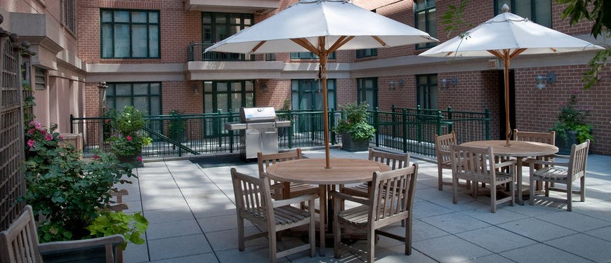 a patio with tables and umbrellas in front of a building