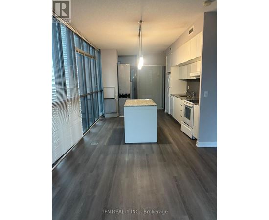 A kitchen with white appliances and a wooden floor.