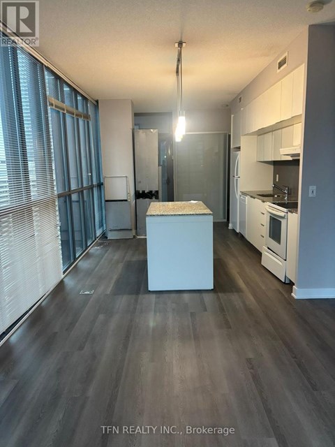 A kitchen with white appliances and a wooden floor.
