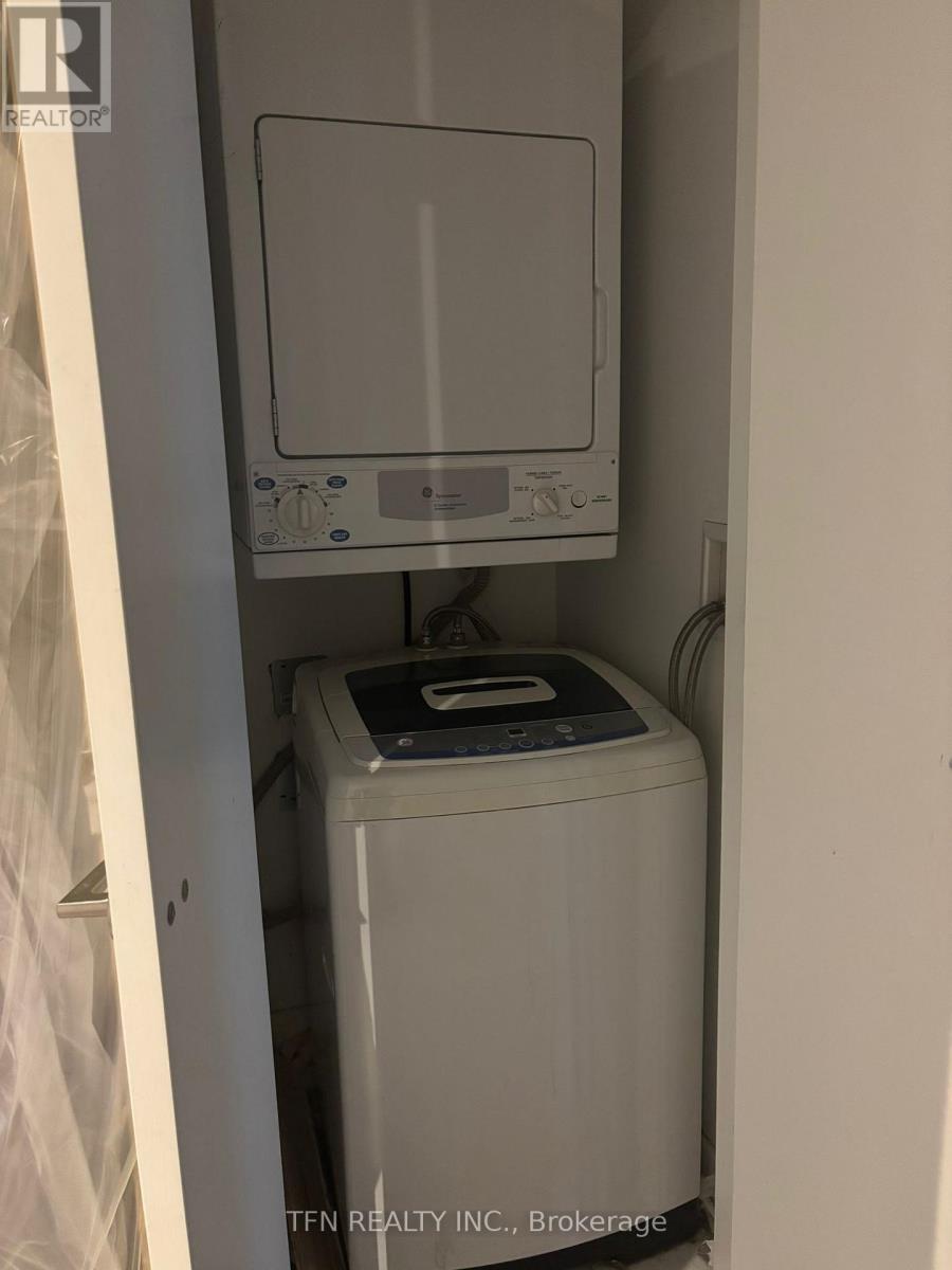 A small white washing machine sits in a narrow space.