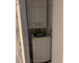 A small white washing machine sits in a narrow space.