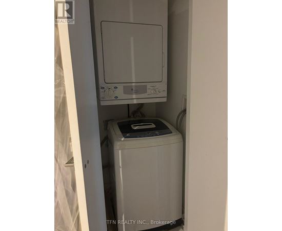 A small white washing machine sits in a narrow space.