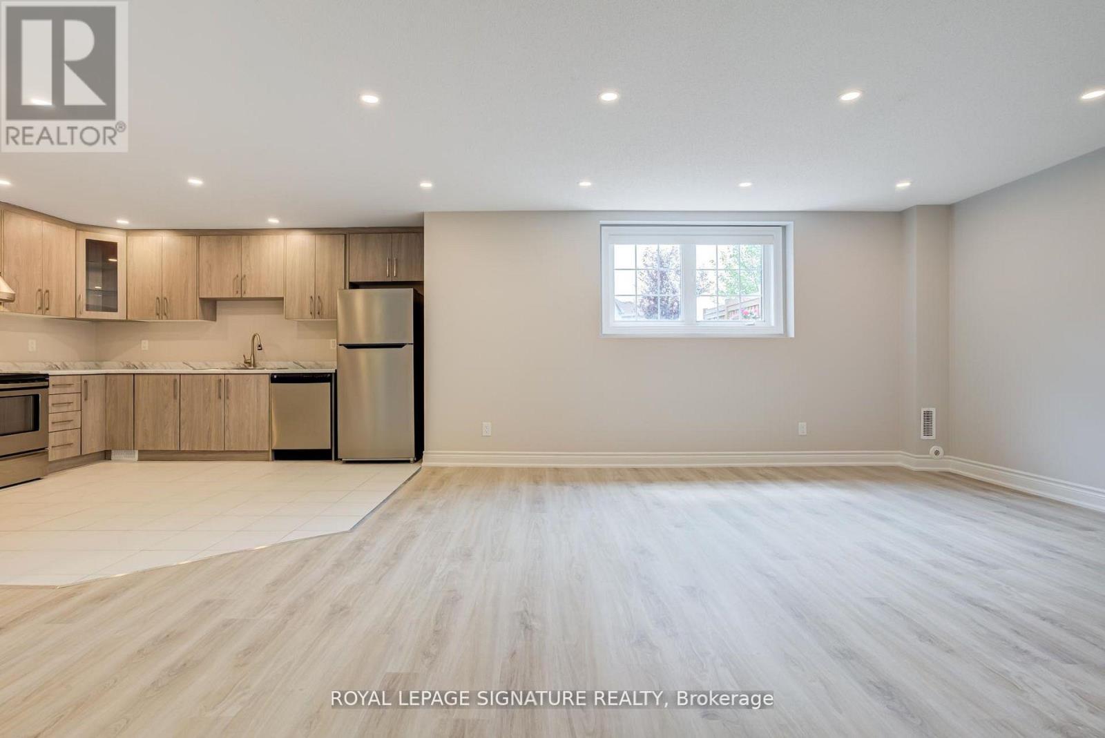 A spacious, empty room with wooden flooring and a large window.