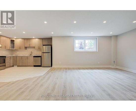 A spacious, empty room with wooden flooring and a large window.