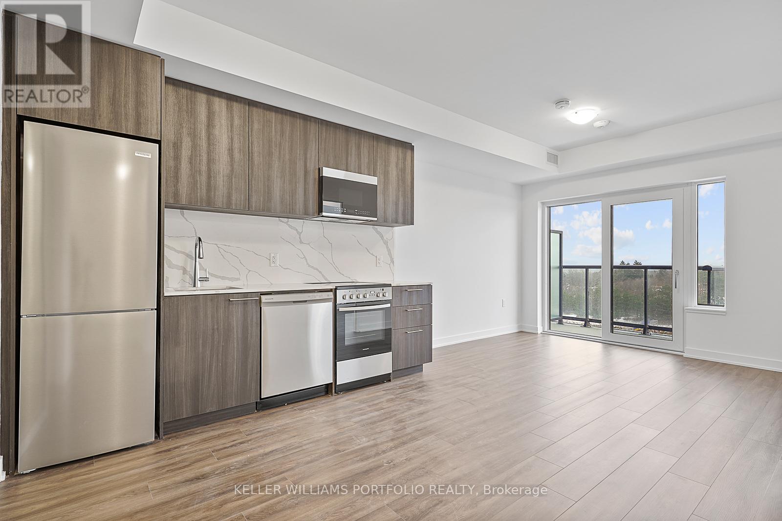 A modern kitchen with a refrigerator, oven, and microwave.