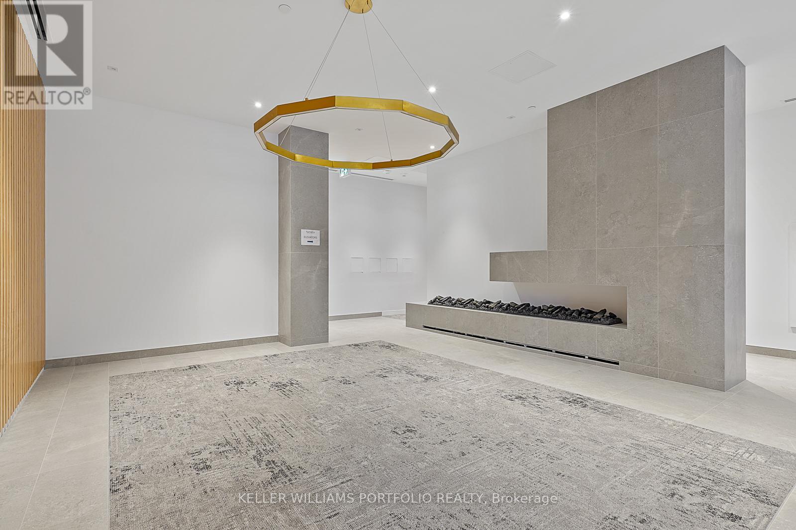 A modern living room with a grey rug and a circular gold chandelier.