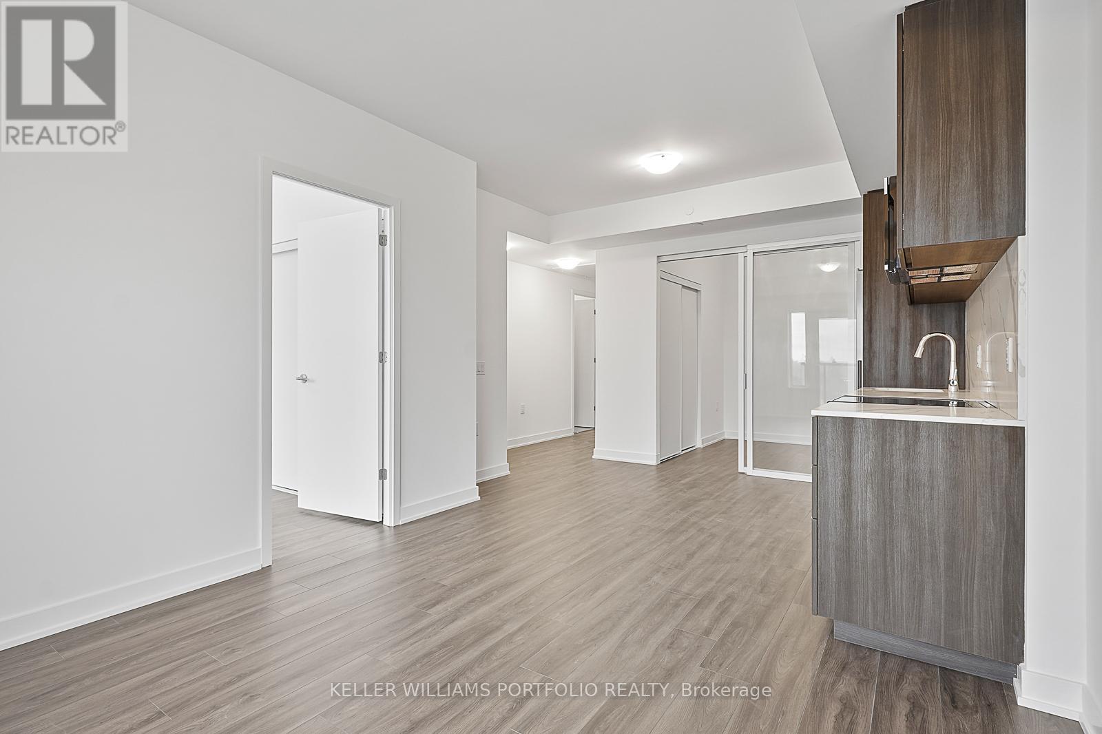 A spacious room with a wooden floor and white walls.
