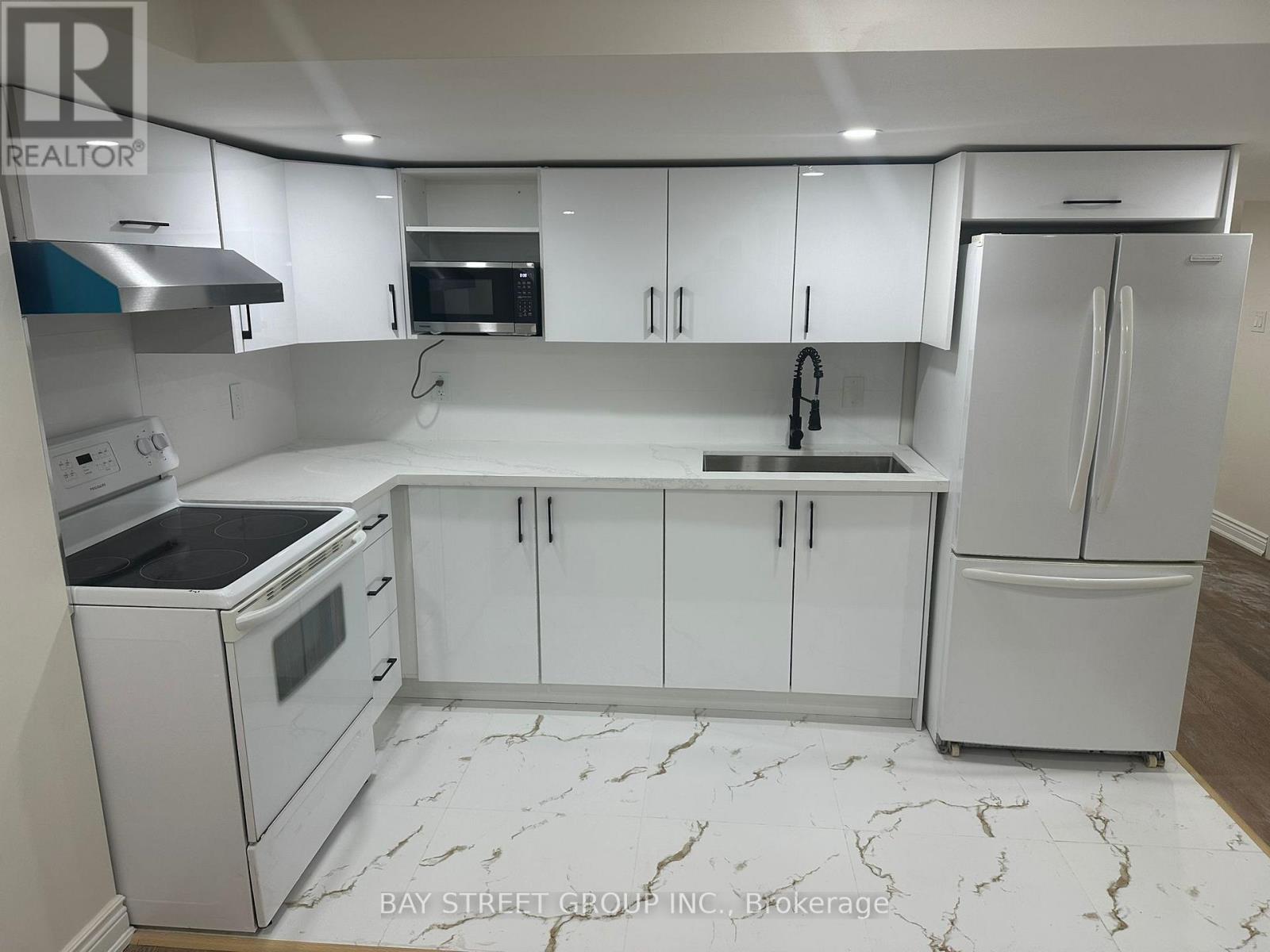 A white kitchen with marble flooring and a refrigerator on the right.