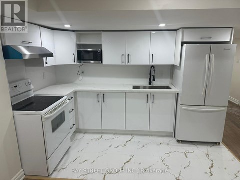 A white kitchen with marble flooring and a refrigerator on the right.