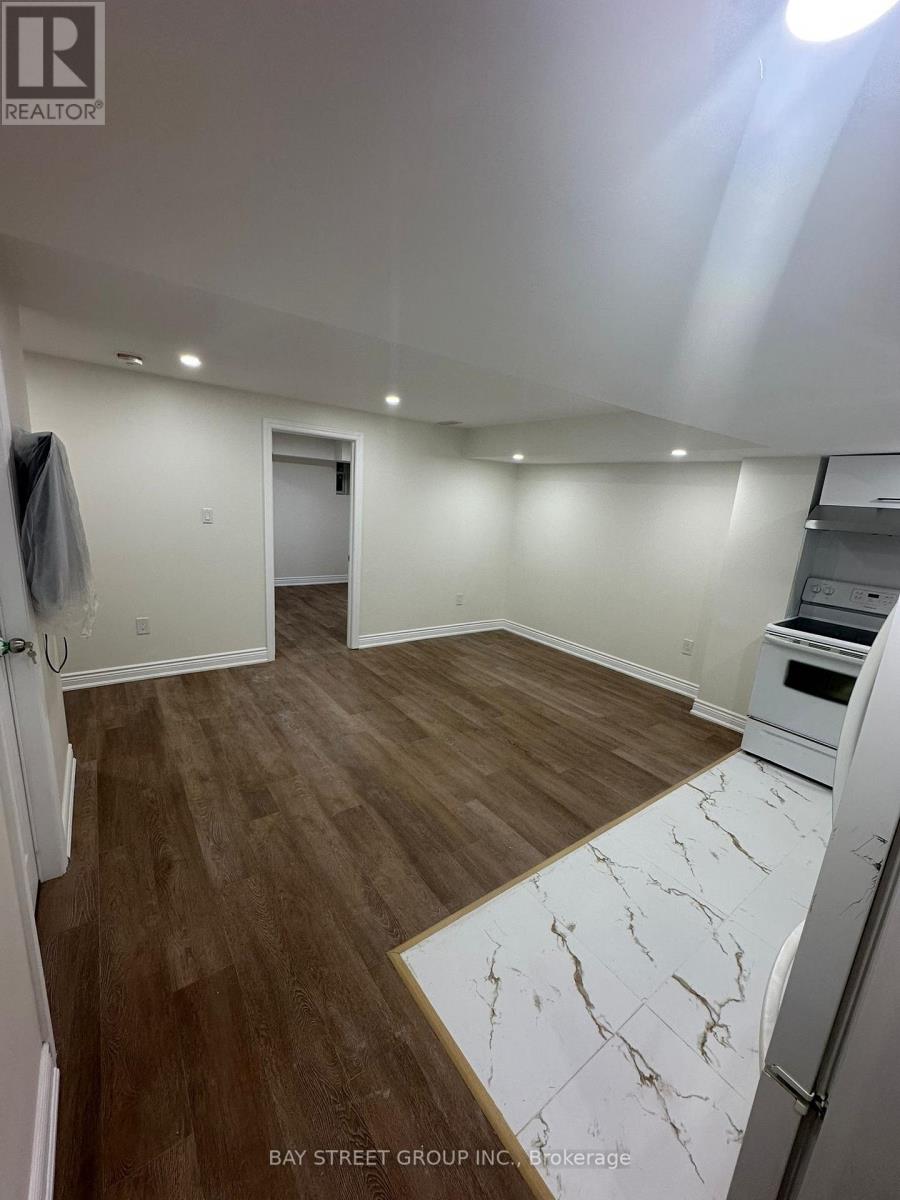 A spacious room with wooden flooring and a marble patterned area rug.