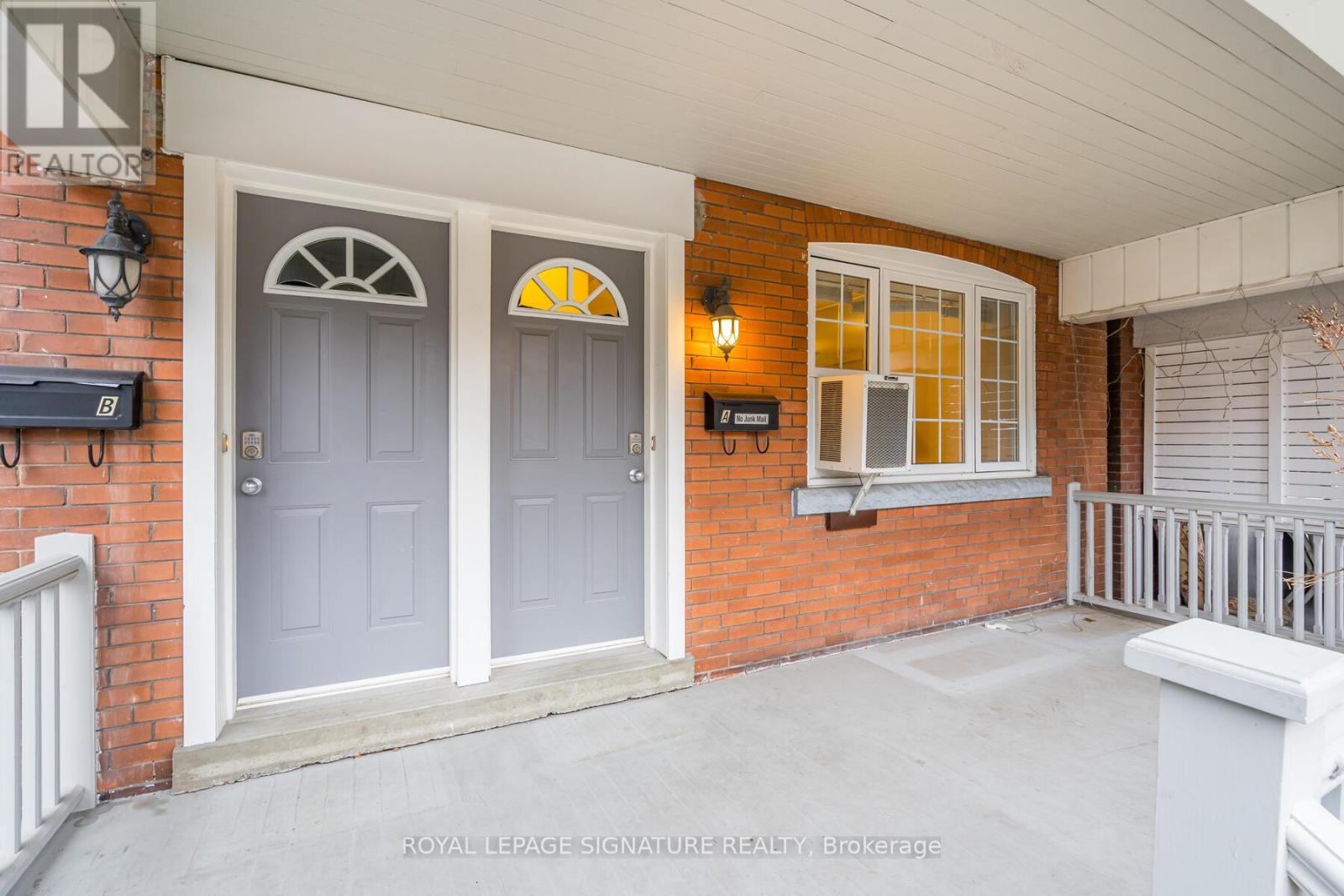 A house entrance with a grey door and a window with a yellow sun design.