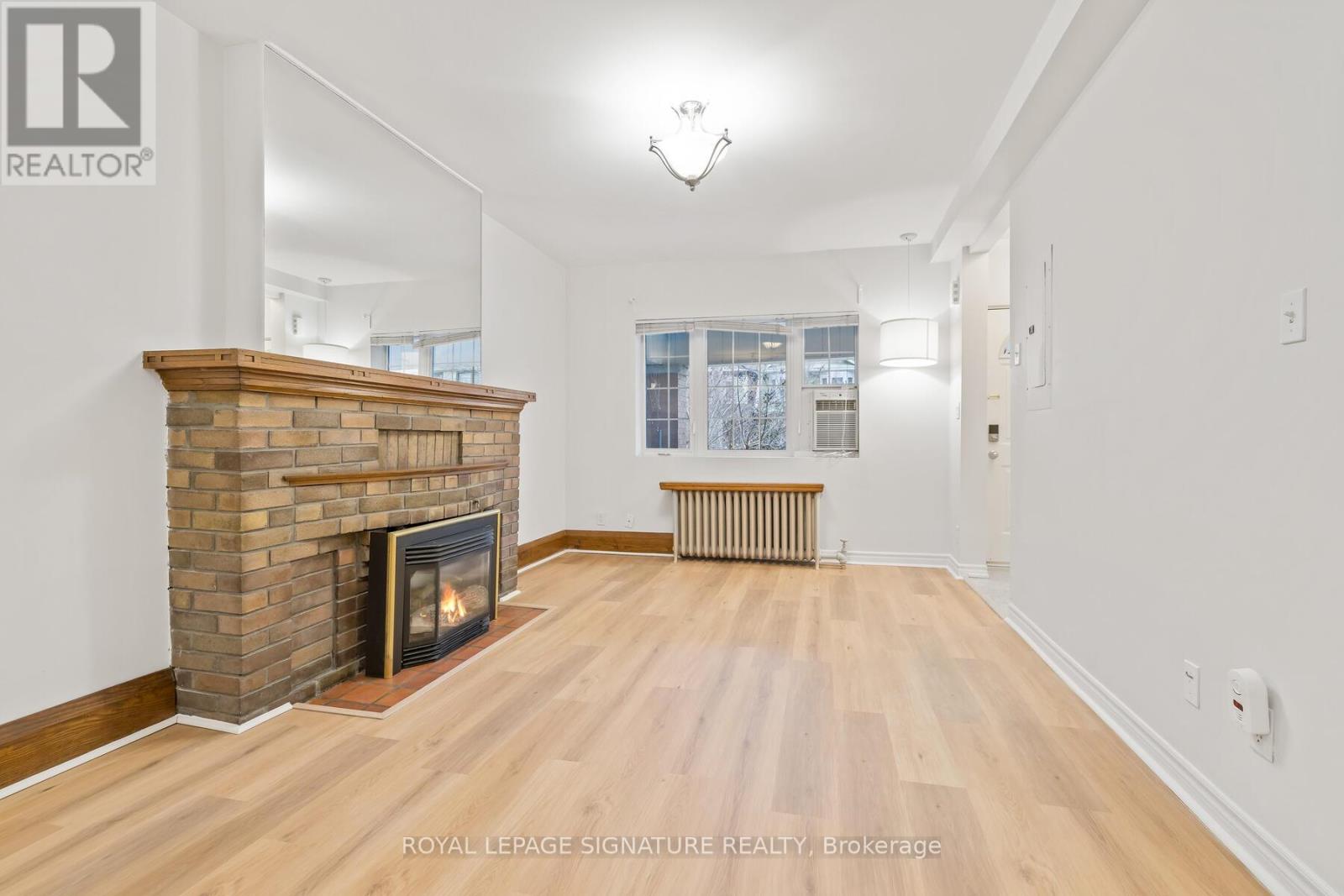 A living room with a fireplace and wooden floors.