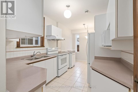 A kitchen with white cabinets and appliances is for sale.