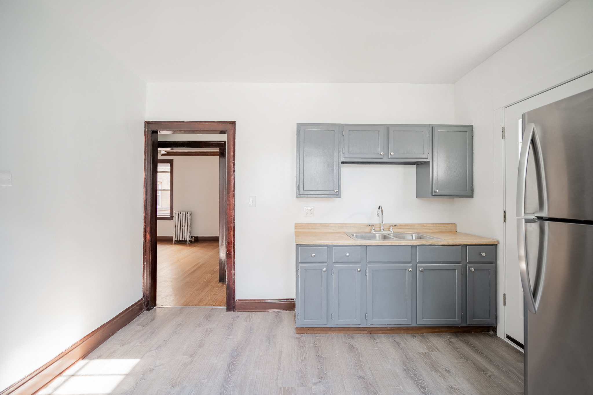 an empty kitchen with blue cabinets and a stainless steel refrigerator
