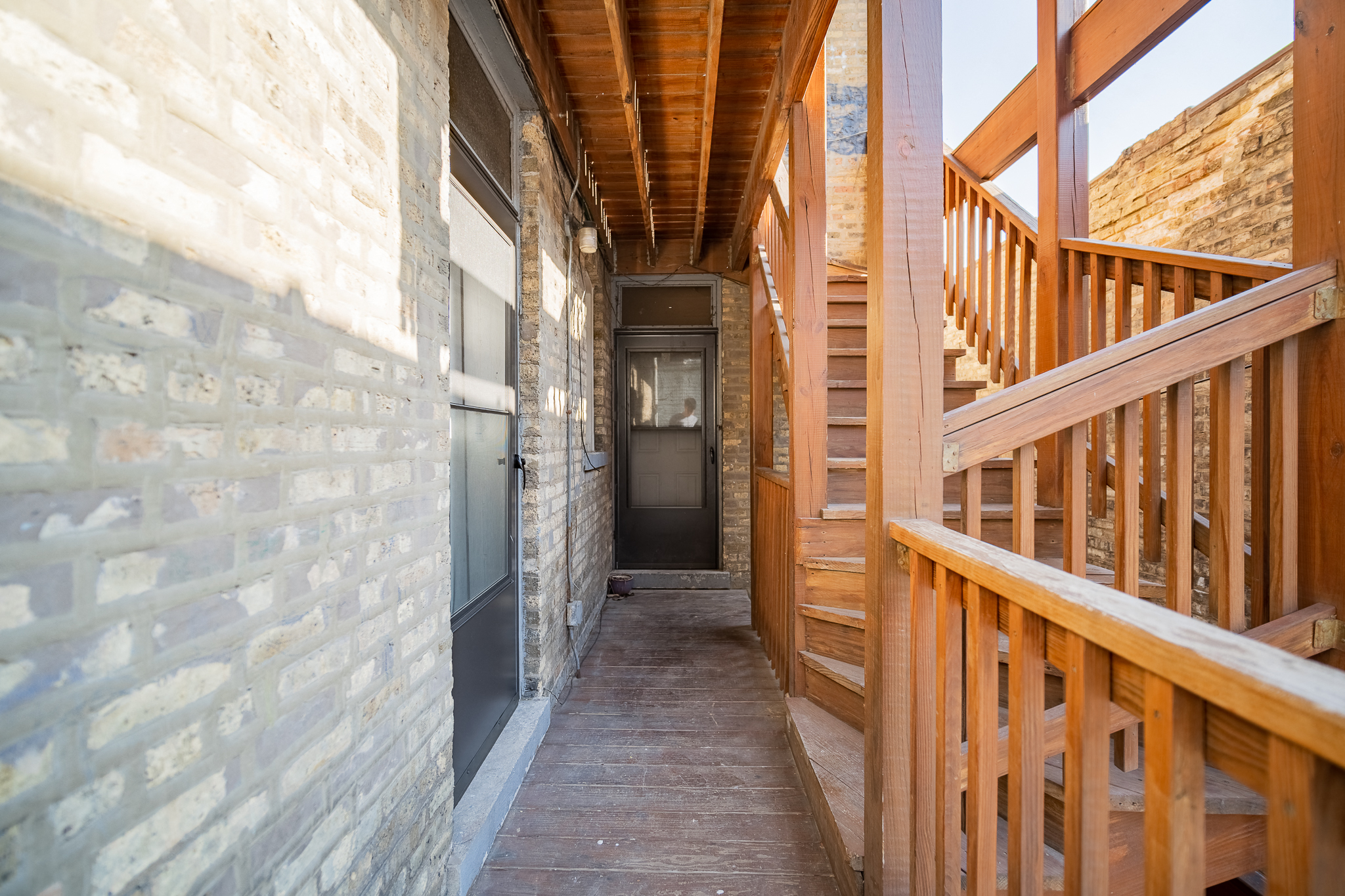 a view of a hallway with wooden stairs and a brick wall