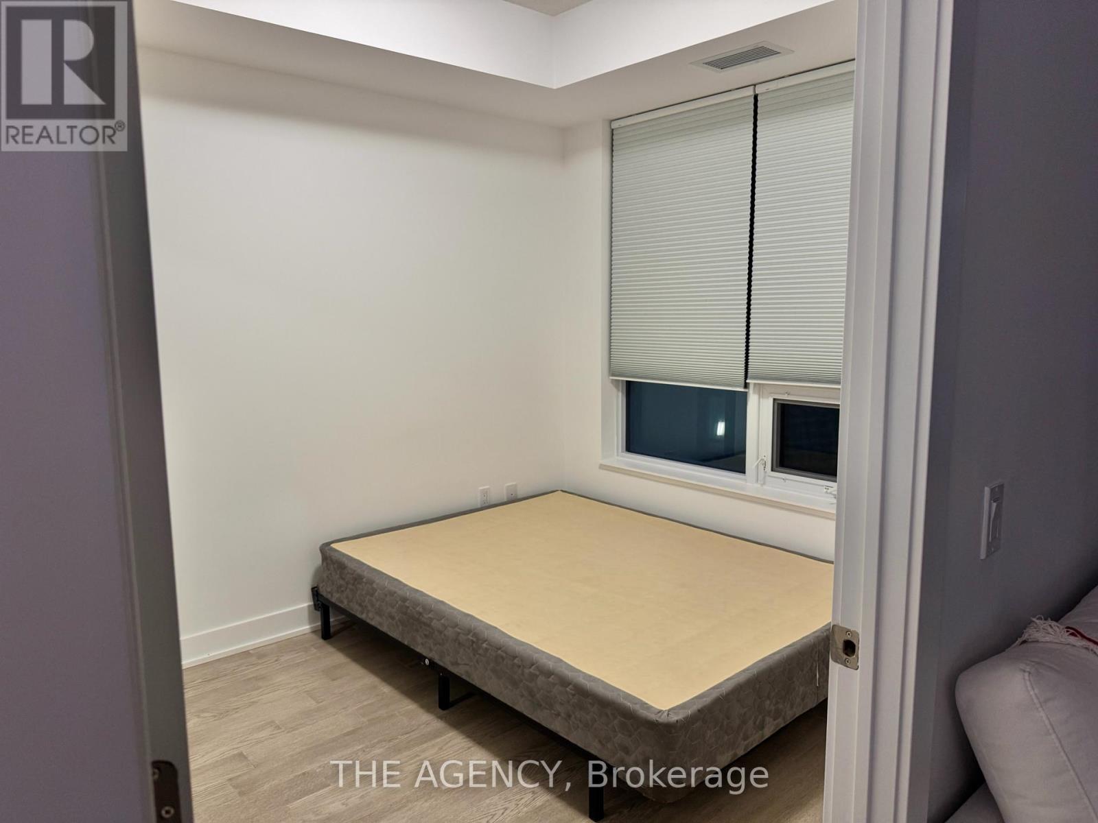 A bedroom with a bed and a window with blinds.