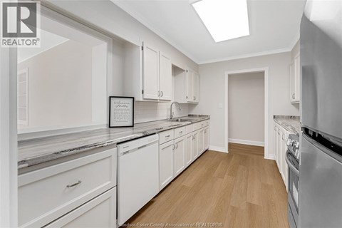 A white kitchen with a fridge, oven and a skylight.