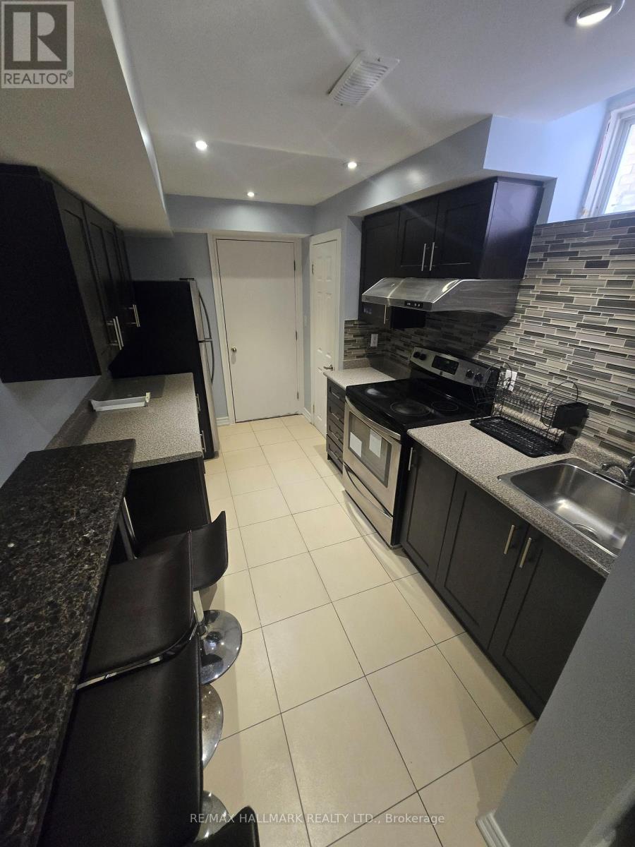 A kitchen with black cabinets and a stone backsplash.
