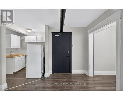 A kitchen with white cabinets and a black door.