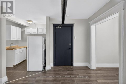 A kitchen with white cabinets and a black door.