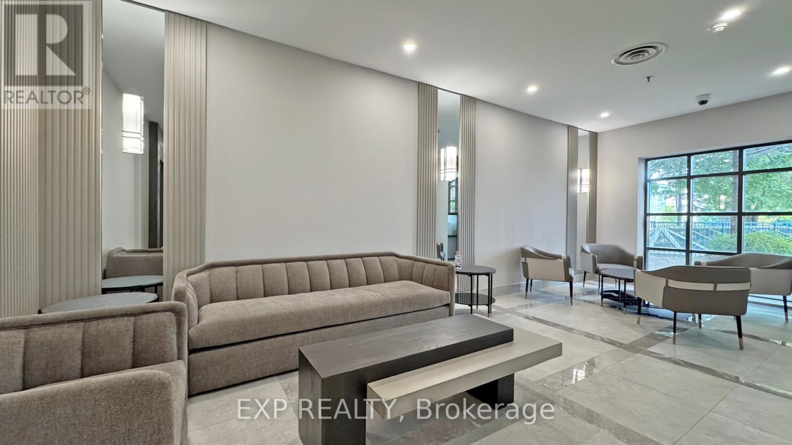A realtor's office with a large couch and a view of trees outside the window.
