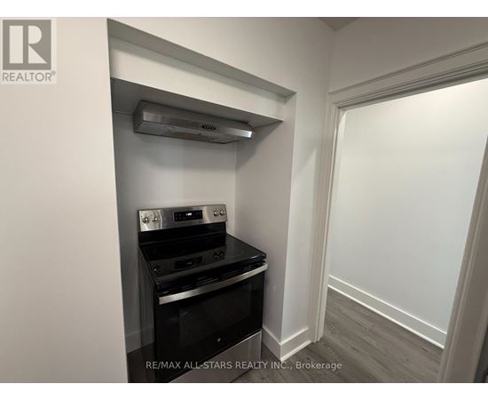 A small kitchen with a stove top oven and a wall-mounted range hood.