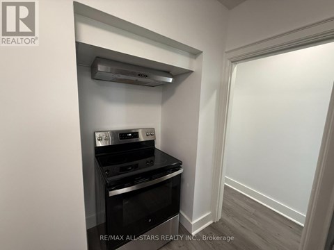 A small kitchen with a stove top oven and a wall-mounted range hood.