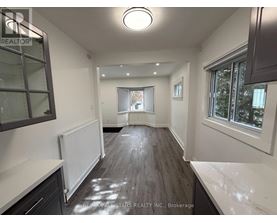 A spacious room with a white ceiling and wooden flooring.