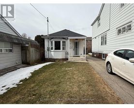 A white car is parked on a driveway in front of a house.