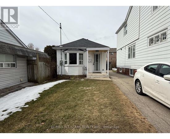 A white car is parked on a driveway in front of a house.