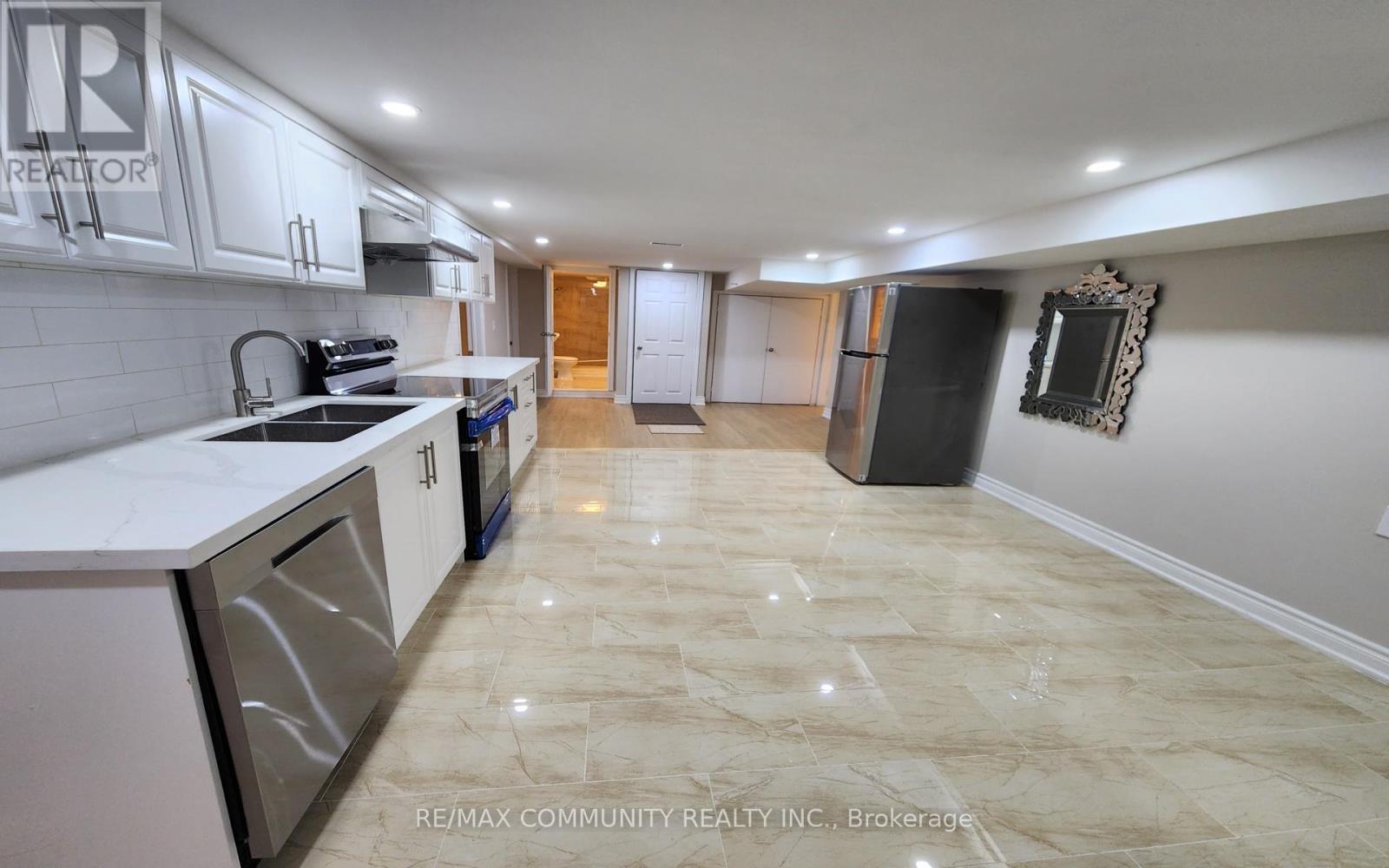 A kitchen with white cabinets and a marble floor.