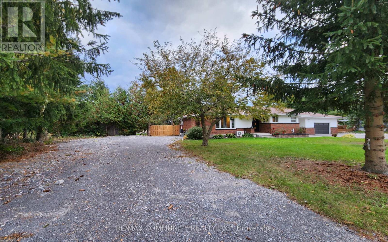 A gravel driveway leads to a house with a gate.