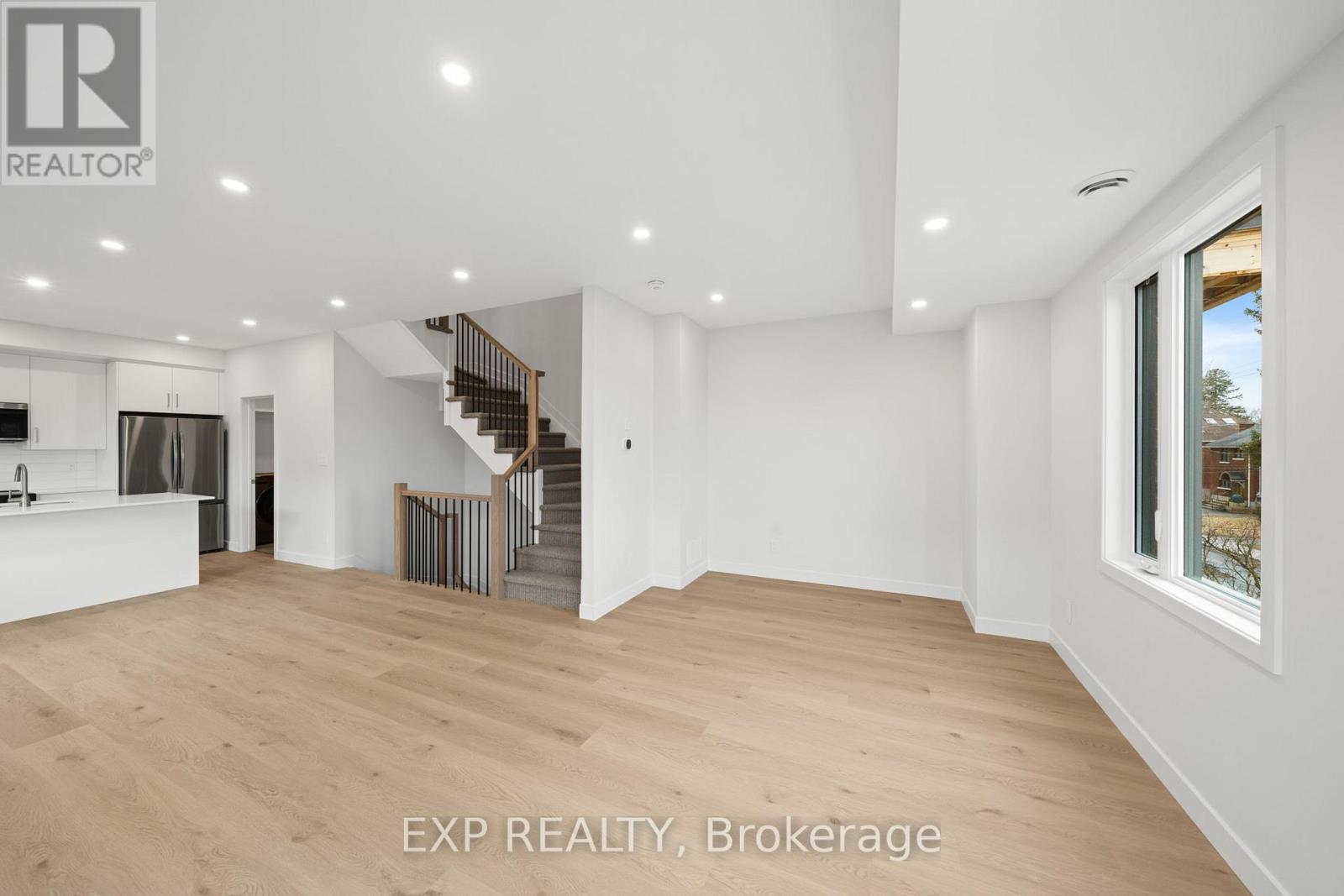 A spacious room with wooden flooring and a staircase leading to another level.