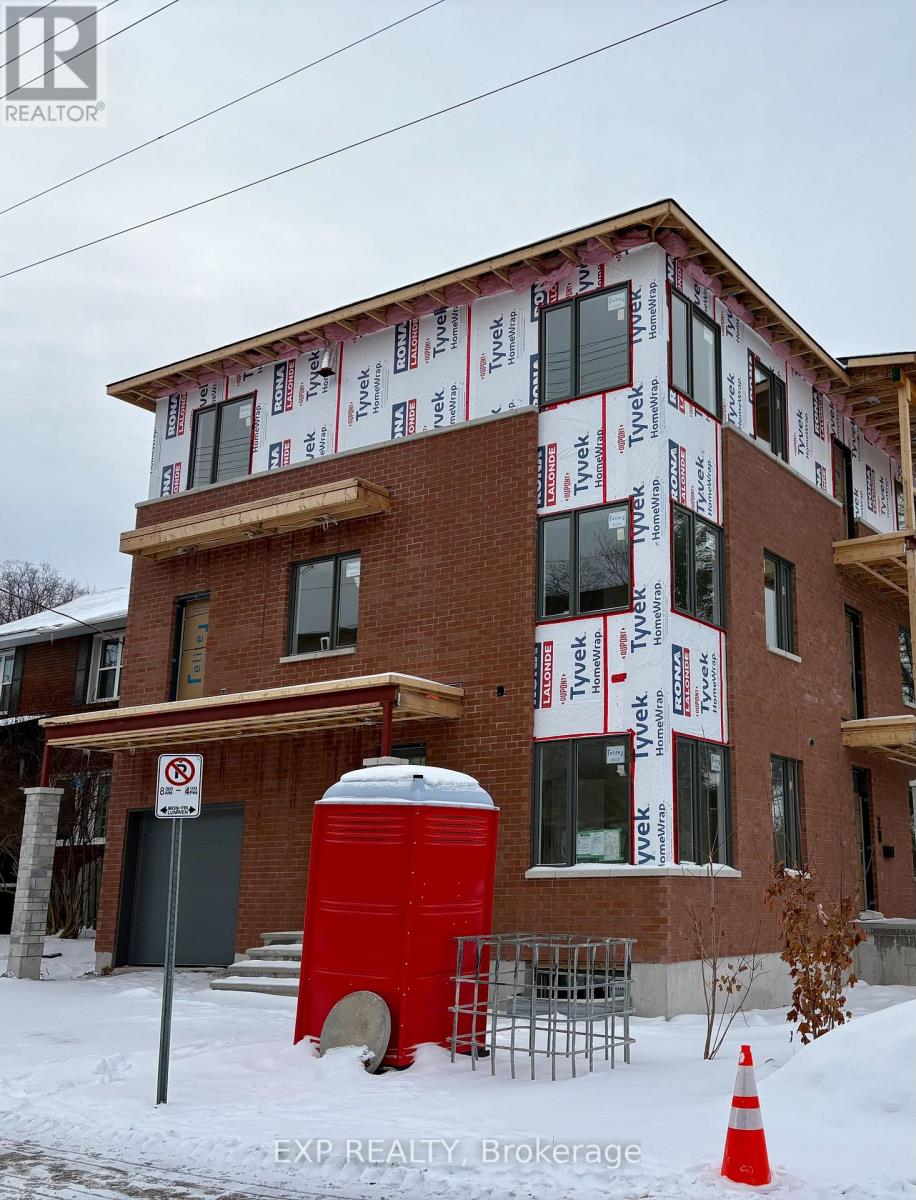 A red port-a-potty is in front of a house under construction.