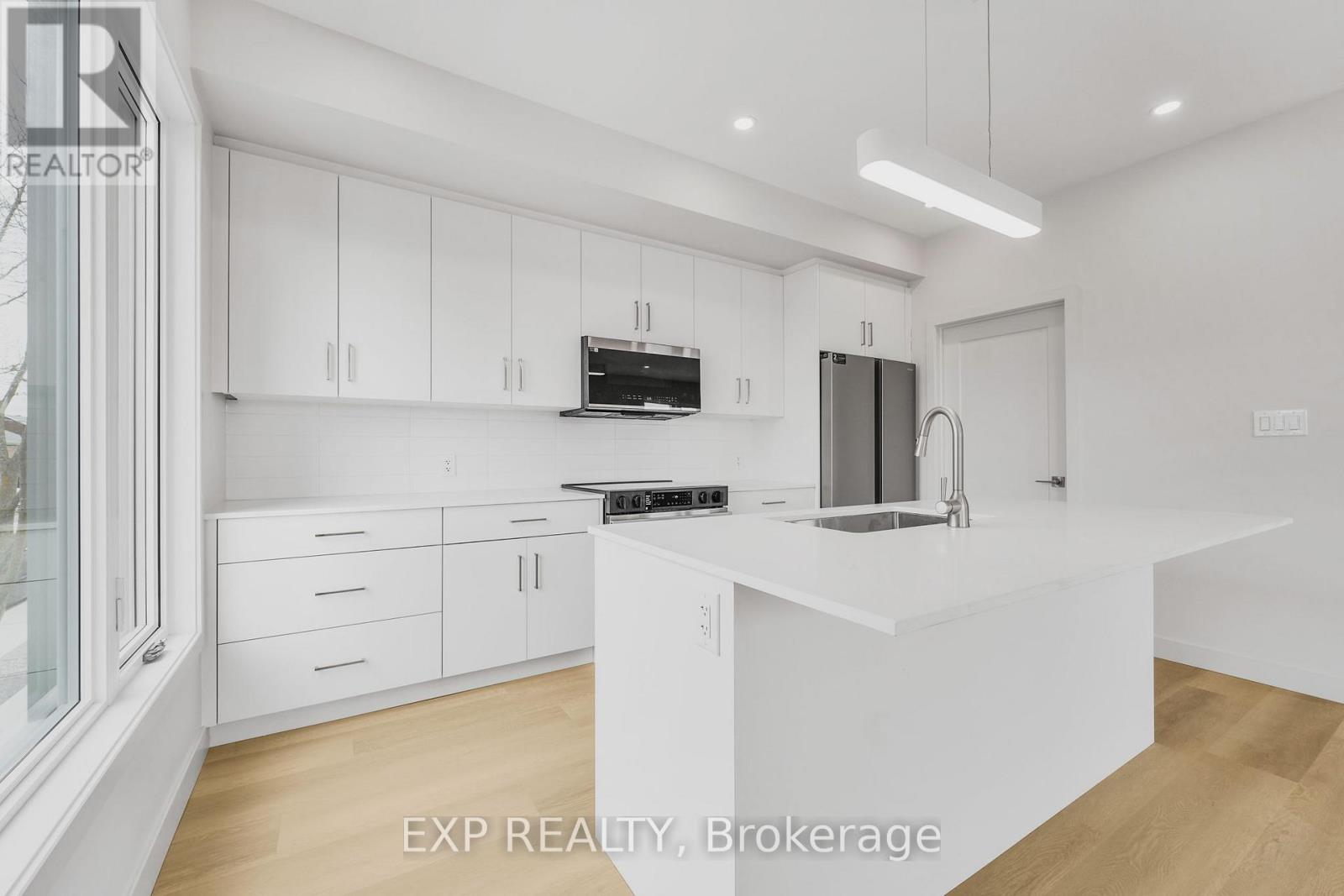 A white kitchen with wooden floors and white cabinets.