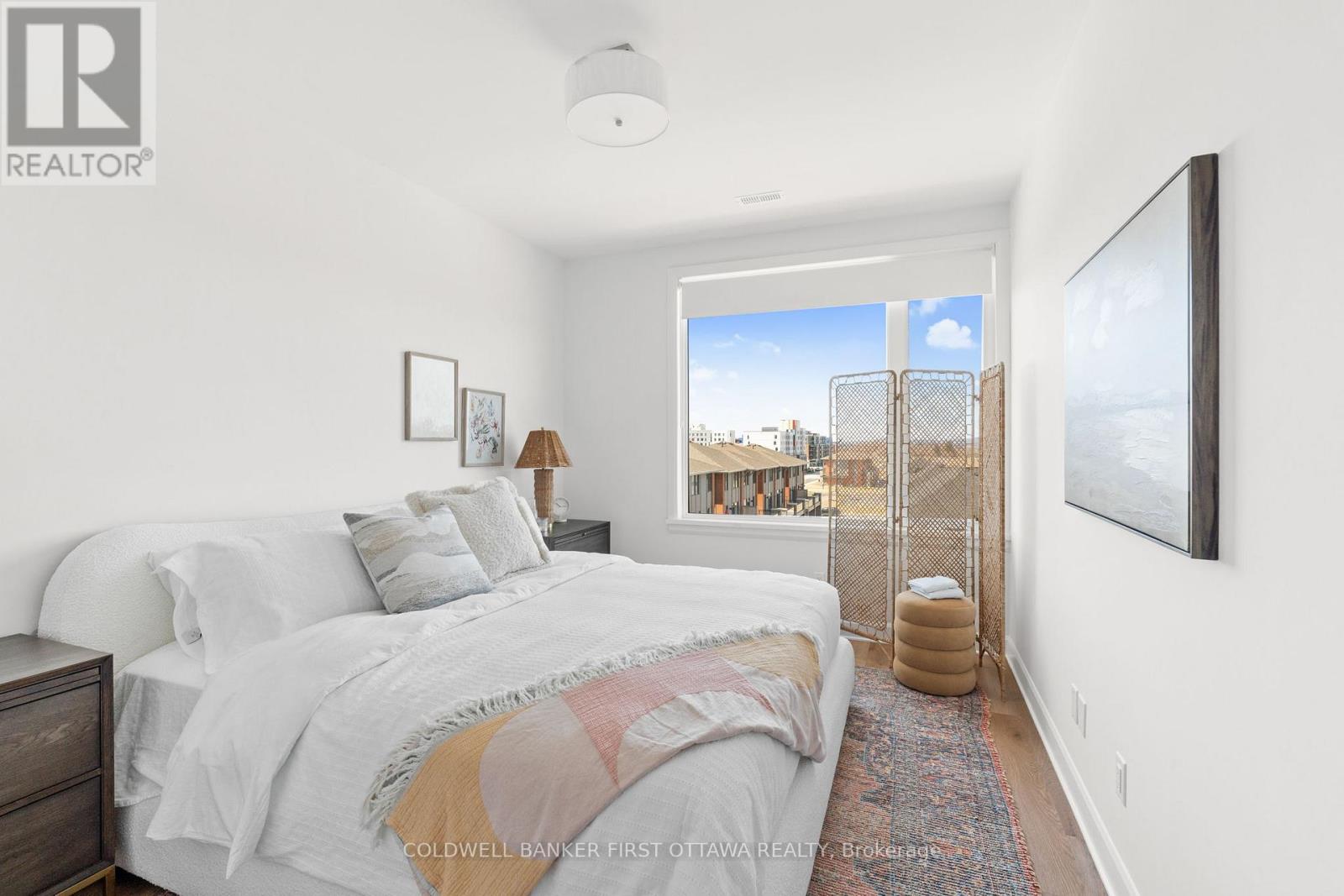 A bedroom with a large bed and a view of the city outside the window.
