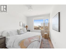 A bedroom with a large bed and a view of the city outside the window.