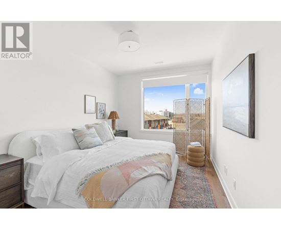 A bedroom with a large bed and a view of the city outside the window.