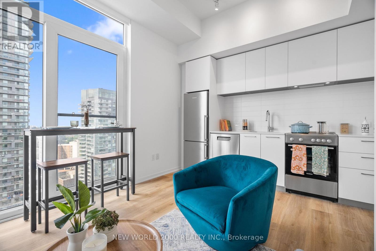A modern kitchen with a teal chair and a view of the city.