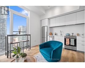 A modern kitchen with a teal chair and a view of the city.