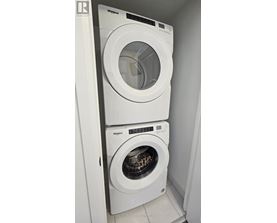 Two white Whirlpool washing machines in a small laundry room.