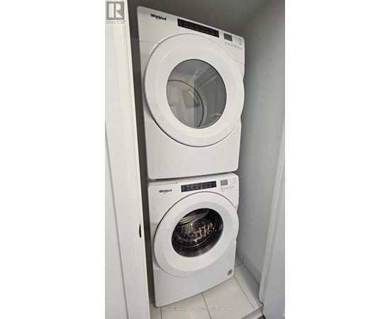 Two white Whirlpool washing machines in a small laundry room.