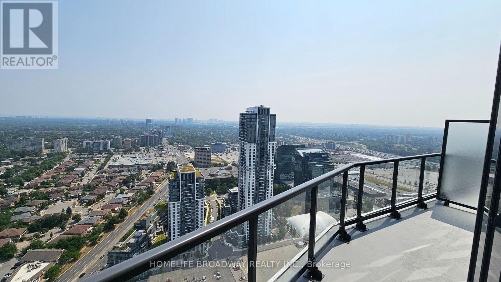 A balcony overlooks a cityscape with a highway and buildings.