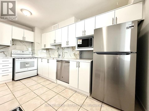 A kitchen with a stainless steel refrigerator and white cabinets.