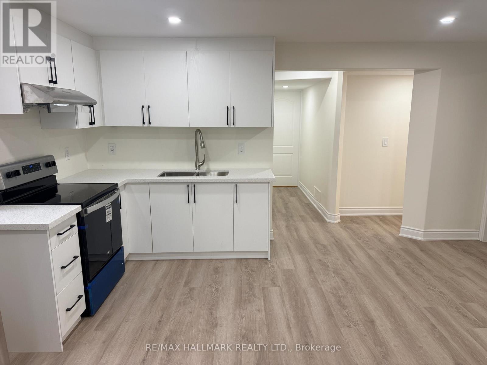 A kitchen with white cabinets and a wooden floor.