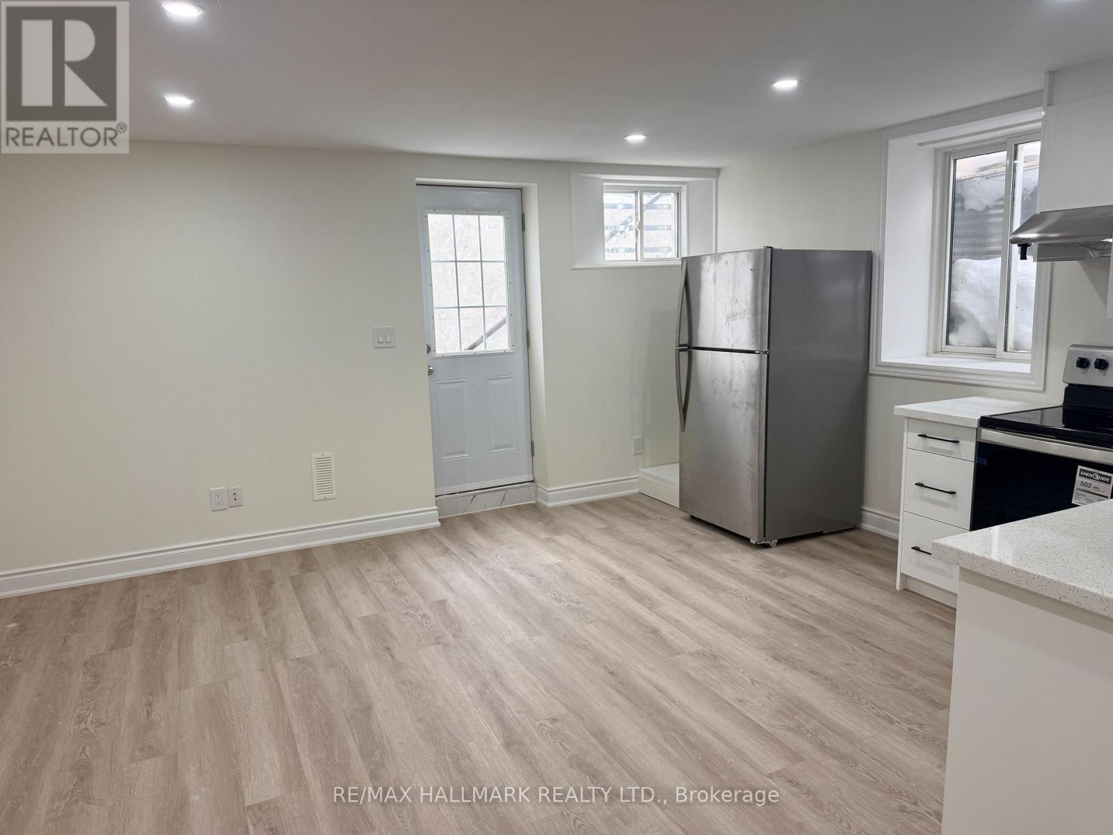 A kitchen with a refrigerator, sink, and cabinets.