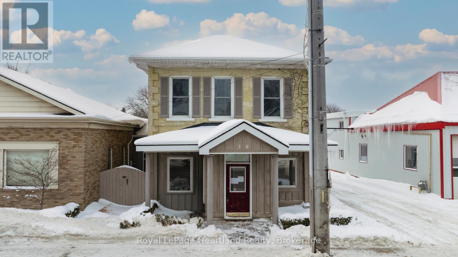 A house with a red door and a brown roof with snow on it.