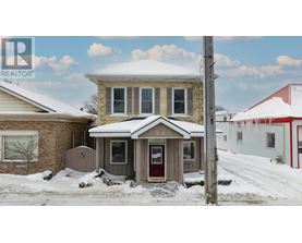 A house with a red door and a brown roof with snow on it.