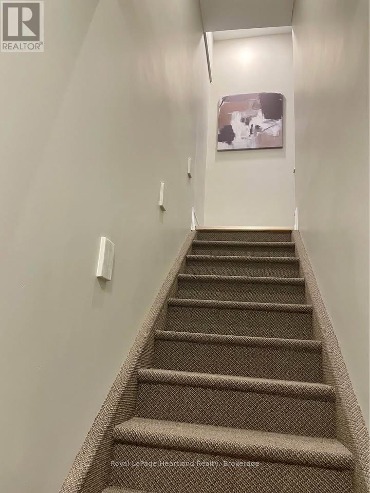 A staircase with a carpeted runner and a painting on the wall.
